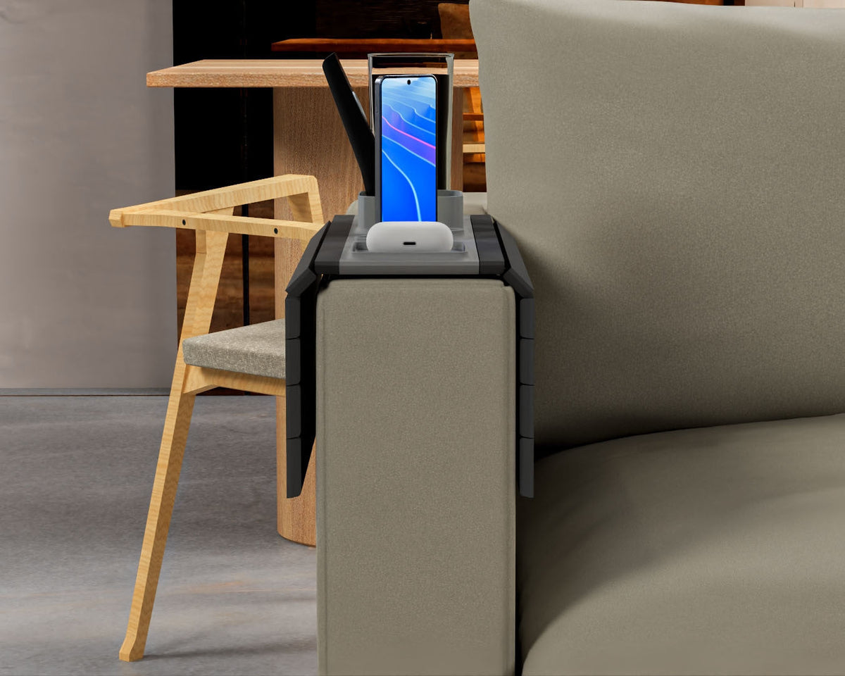All In — Modular Sofa Side Table — the tray on an olive sofa arm holding a phone and earbuds, a wooden dining chair behind.