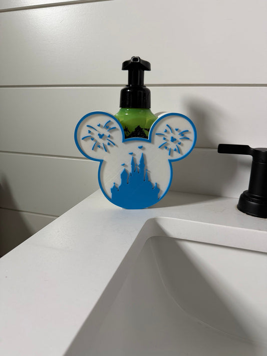 Castle Mouse Head Soap Dispenser Holder — a blue and white rounded holder with two ear shapes and a castle and fireworks design, holding a pump soap bottle at a sink.