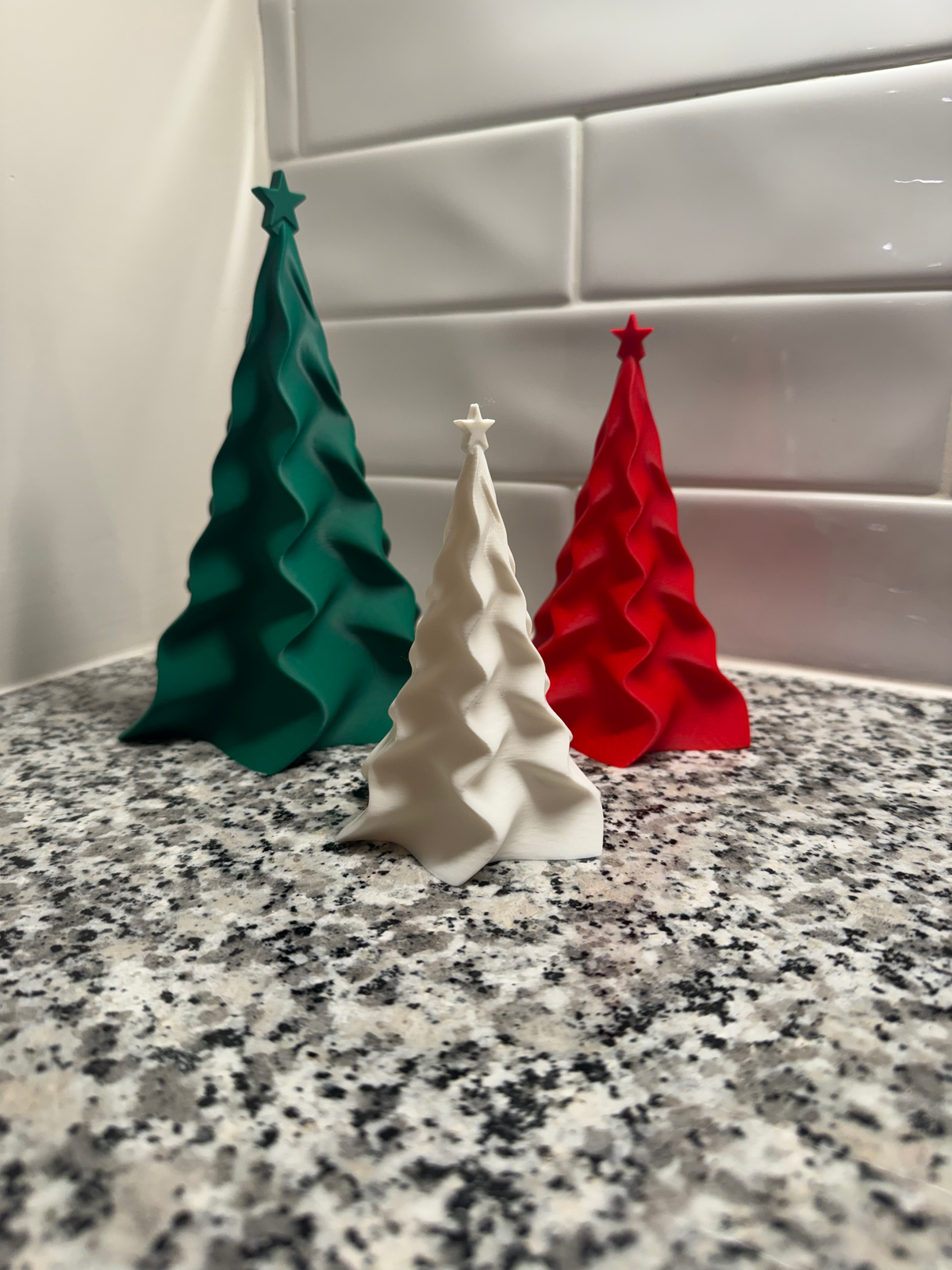 Christmas Tree Décor — Set of 3 — three ribbed conical trees in green, cream and red, in descending sizes on a speckled counter.