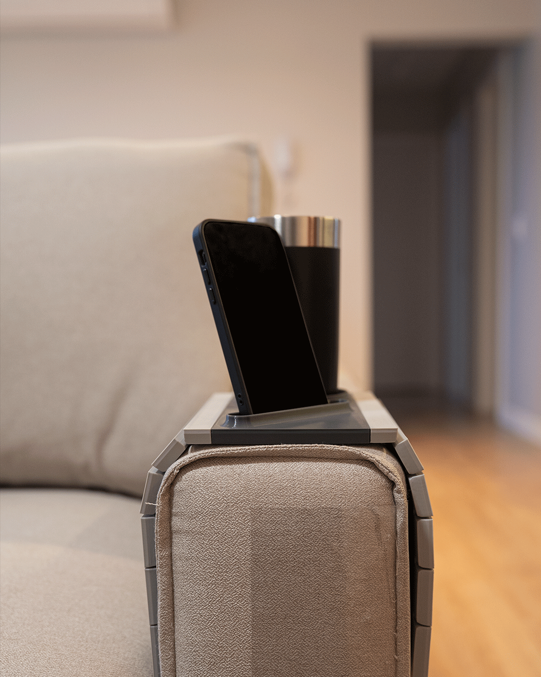 First Stop — Modular Sofa Side Table — close view on a tan sofa arm with a phone upright beside a dark tumbler.