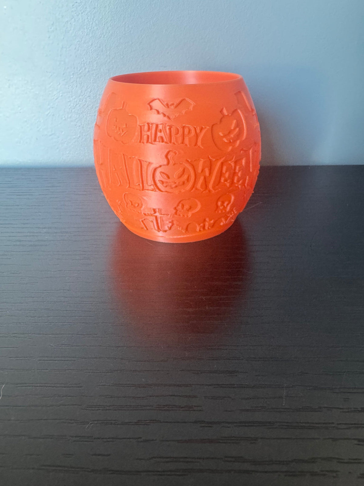 Happy Halloween Pumpkin Lantern — the same lantern unlit on a dark wood surface, showing the raised pumpkin and bat detailing.