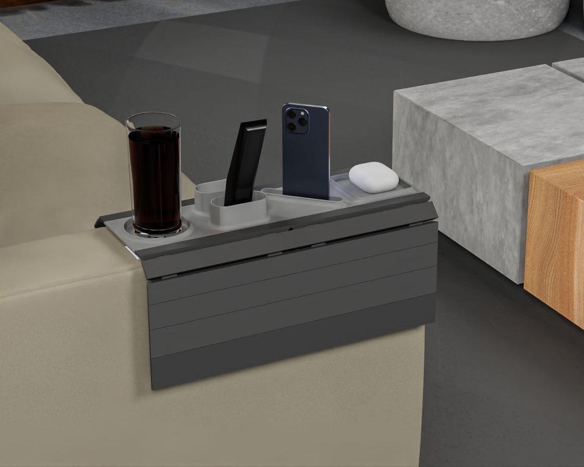 All In — Modular Sofa Side Table — the grey tray fitted over a sofa arm, holding a dark drink, a phone, a remote and an earbuds case.