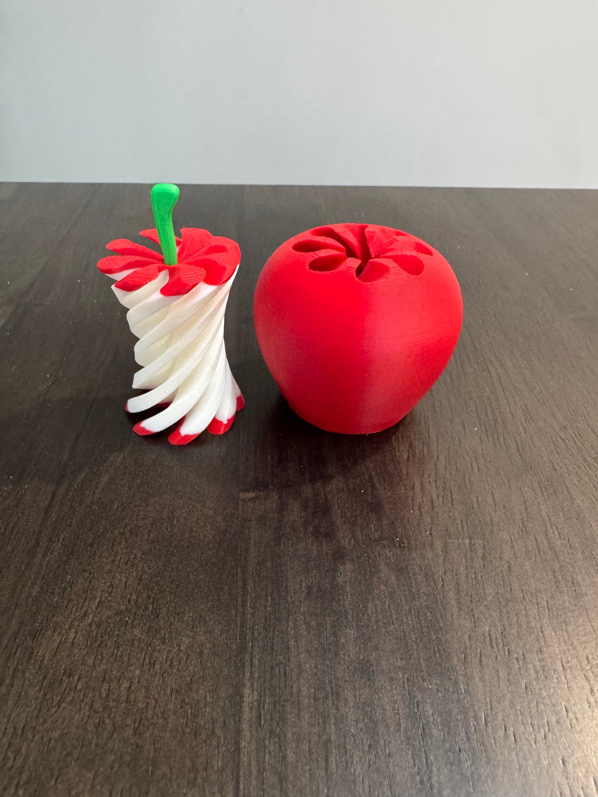 Apple Pass-Through Fidget — the fidget pulled open to show its white spiral core, beside a second closed red apple.
