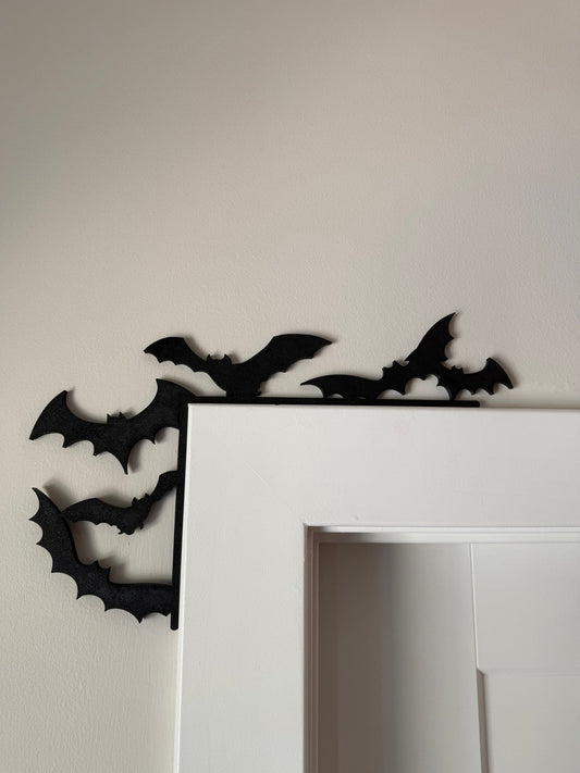 Bat Swarm Corner Door Topper — a scatter of black bats mounted around the top corner of a white door frame.