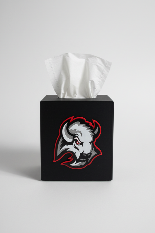 Black Buffalo Tissue Box Cover — a black square tissue box cover with a raised front emblem, tissue drawn through the top, on a soft light-gray studio background.