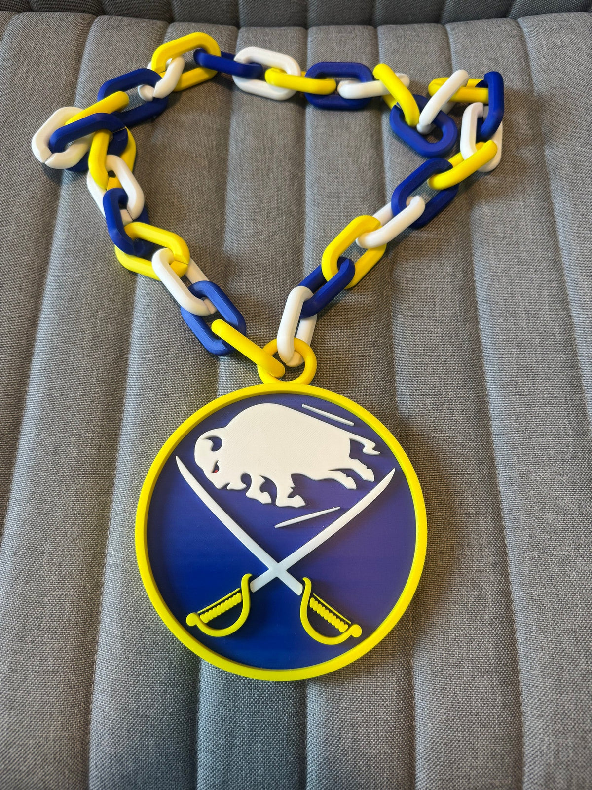 Blue & Gold Buffalo Chain Necklace — a flat blue and gold pendant on a chain, laid on a light surface.
