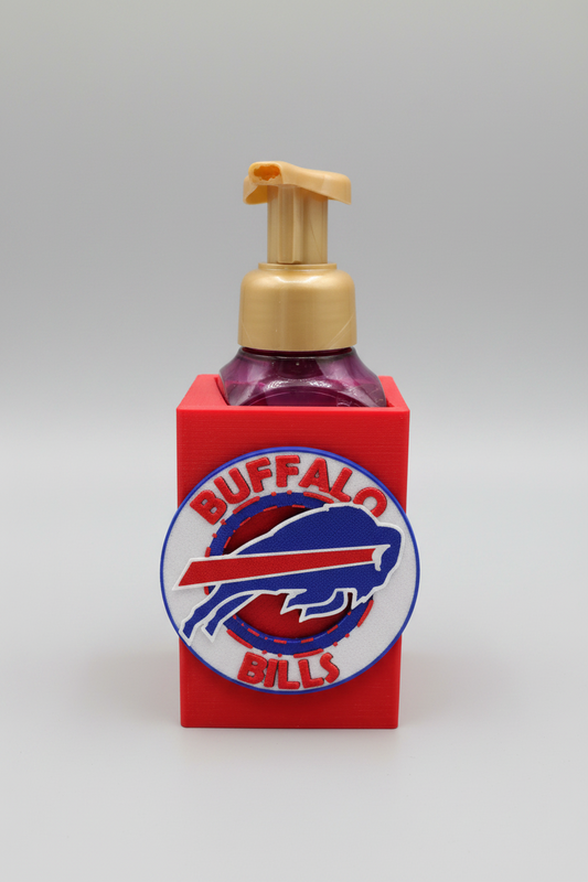Buffalo Football Soap Dispenser Holder — a red sleeve-style holder with a raised circular front emblem, cradling a dark bottle with a gold pump, on a soft light-gray studio background.