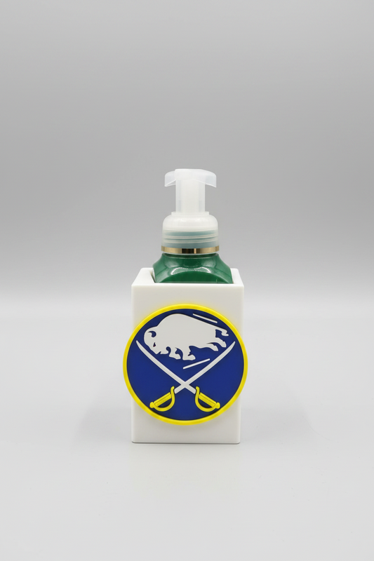Buffalo Hockey Soap Dispenser Holder — a white square sleeve with a raised front emblem, holding a green foaming soap bottle, on a soft light-gray studio background.