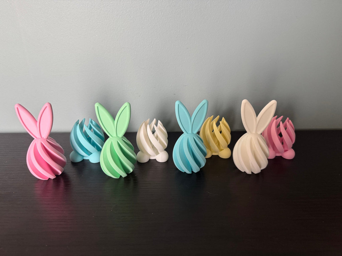 Bunny Egg Spiral Fidgets — Set of 4 — the bunnies twisted open to show their spiral interiors, lined up beside closed ones.