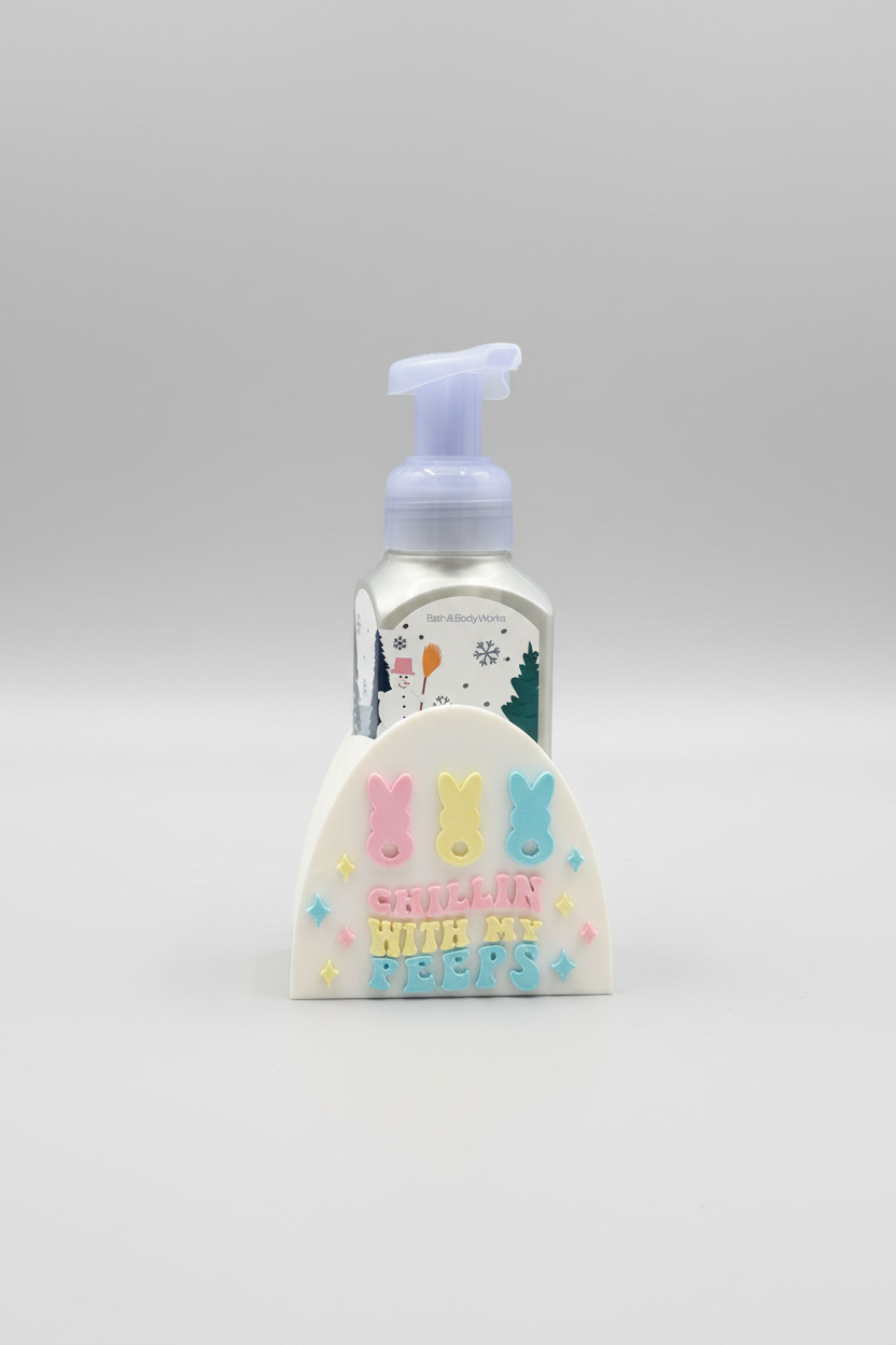 Chillin' With My Peeps Soap Dispenser Holder — a frosted glass pump bottle standing behind a white decorative sign with pastel bunny and star embellishments, on a soft light-gray studio background.