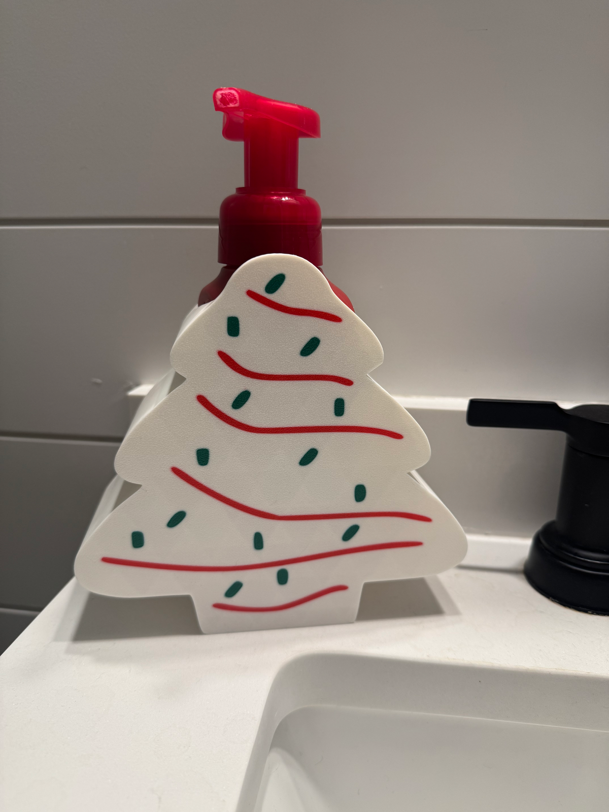 Christmas Tree Cake Soap Dispenser Holder — a green tree-shaped holder with white icing stripes and coloured sprinkles, sized for a foaming soap bottle.
