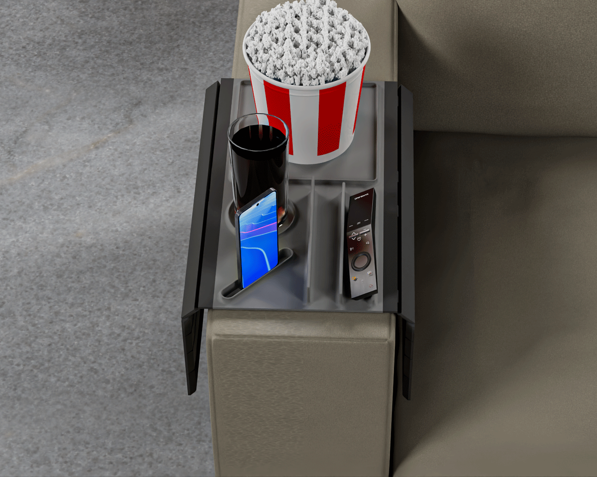 Couch Buster — Modular Sofa Side Table — the grey tray on a sofa arm holding a striped popcorn tub, a dark drink, a phone and a remote.