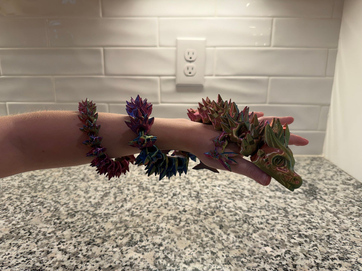 Crystal Dragon — two articulated dragons in purple and green coiled along a forearm and hand.