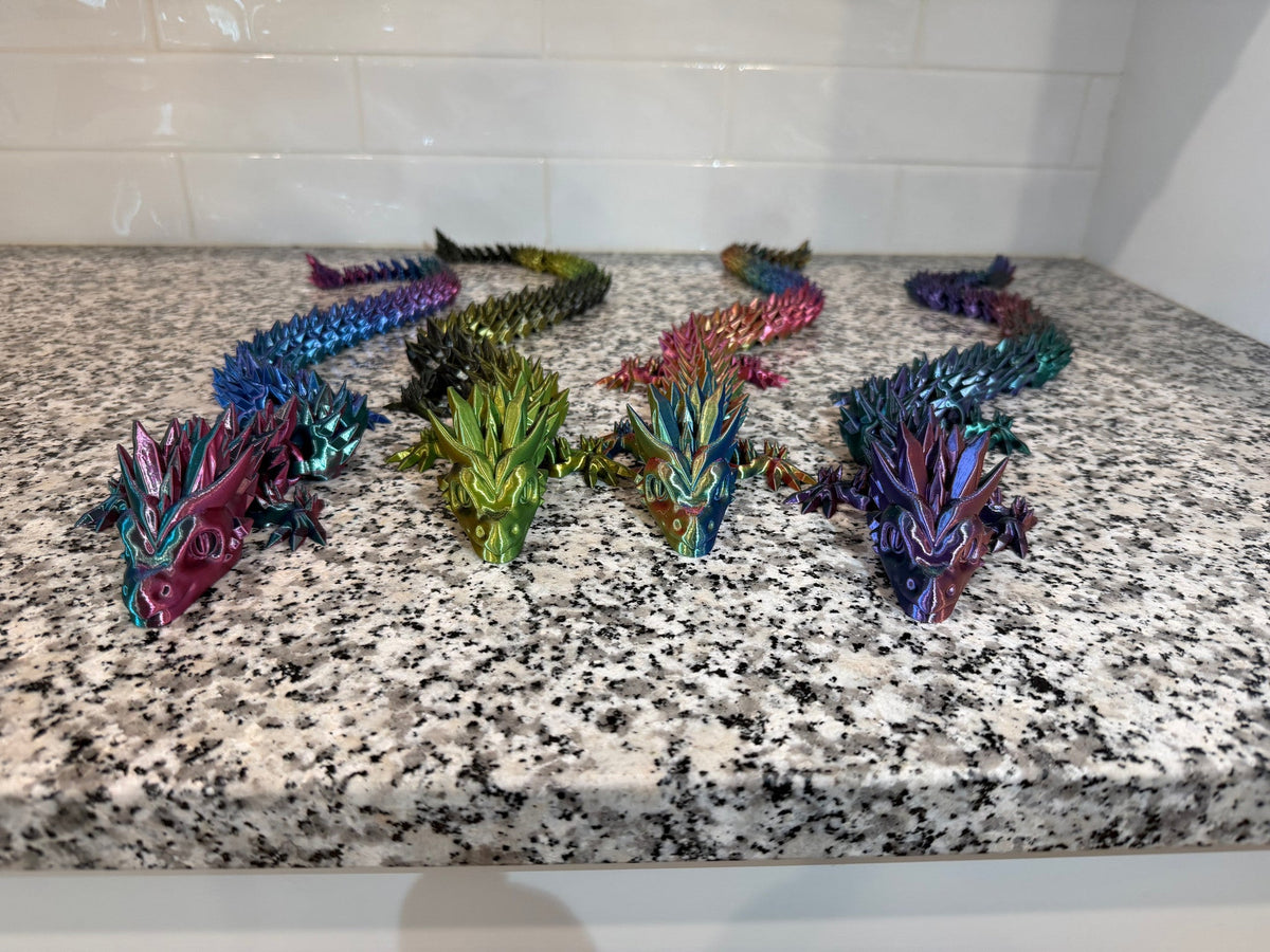Crystal Dragon — five iridescent articulated dragons in blue, green, red and purple arranged across a granite counter.
