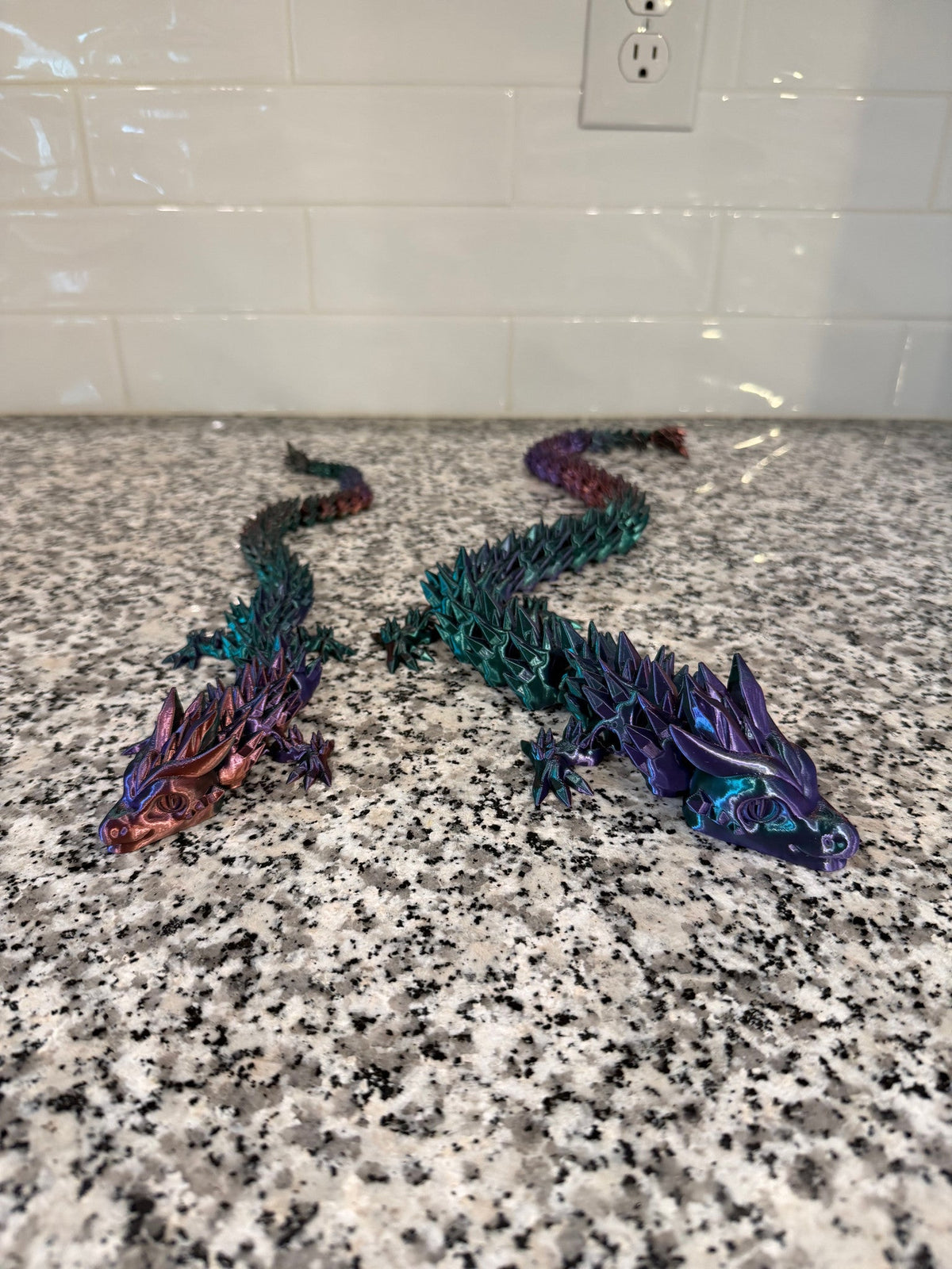 Crystal Dragon — two long articulated dragons in teal and purple, tails curling behind them.