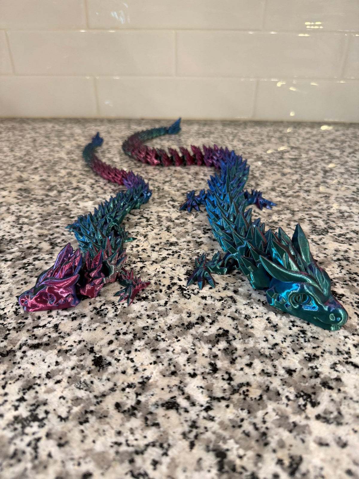 Crystal Dragon — a teal dragon in front of a pink and blue one, showing the spined back and jointed tail.