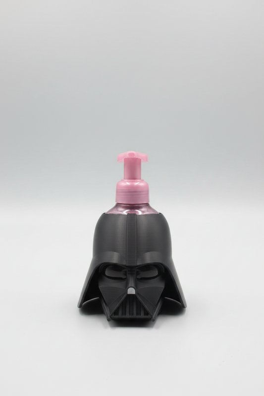Dark Lord Helmet Soap Dispenser Holder — a helmet-shaped pump bottle with a pink pump dispenser, on a soft light-gray studio background.