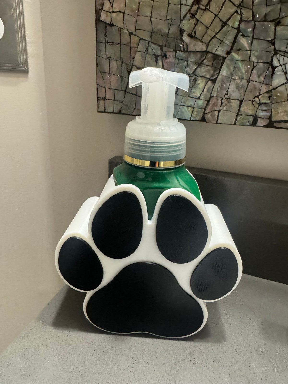 Dog Paw Soap Dispenser Holder — the white and black version holding a green soap bottle with a clear pump.
