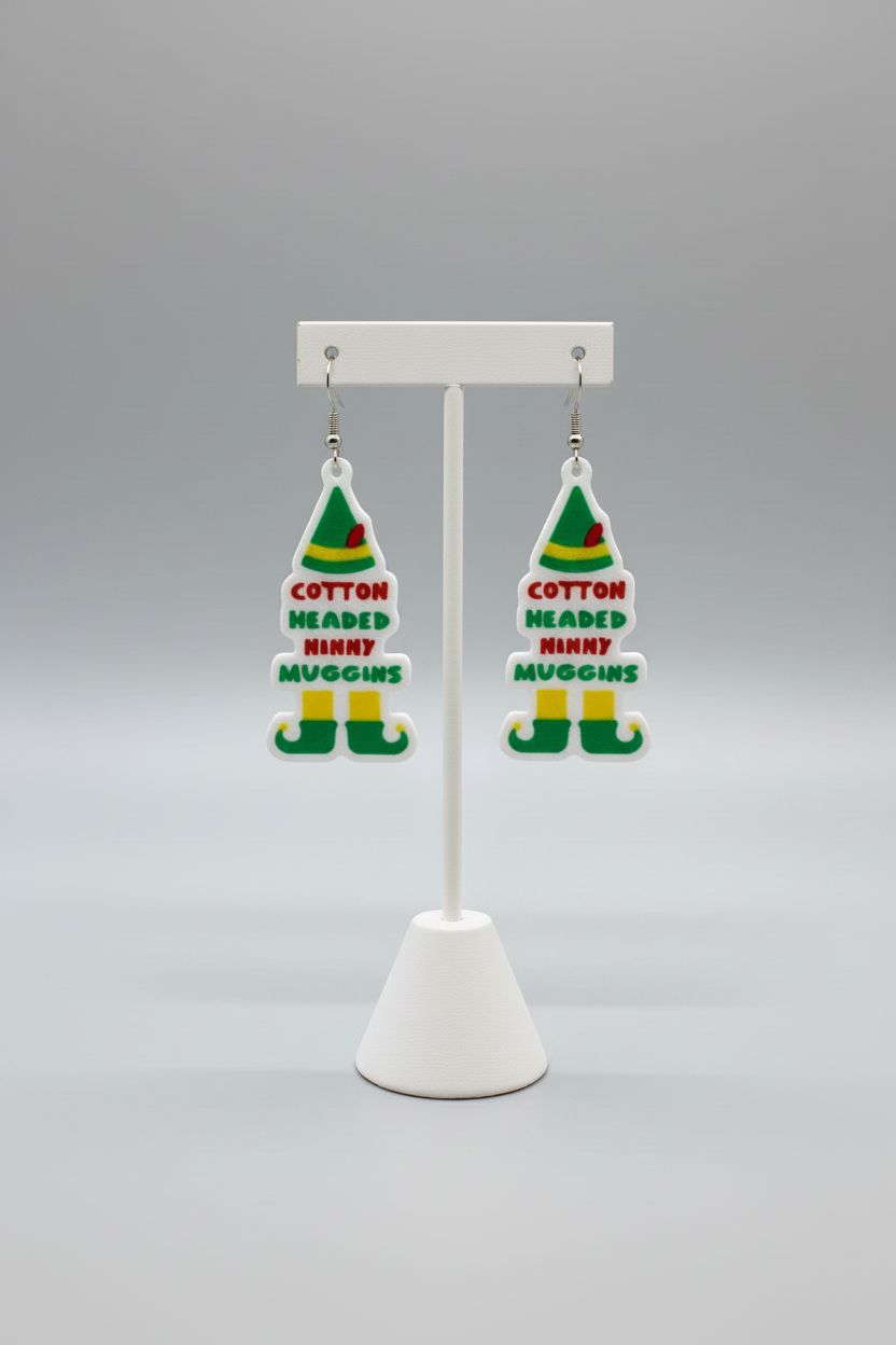 Elf Hat Dangle Earrings — a pair of Christmas-themed elf hat-shaped dangling earrings with a white base and green, red, and yellow details, on a soft light-gray studio background.