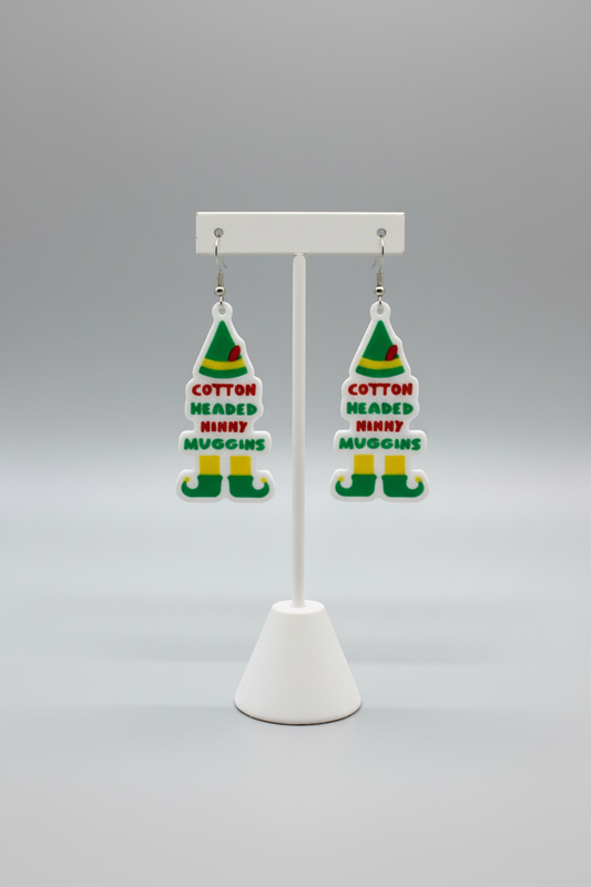 Elf Hat Dangle Earrings — a pair of Christmas-themed elf hat-shaped dangling earrings with a white base and green, red, and yellow details, on a soft light-gray studio background.