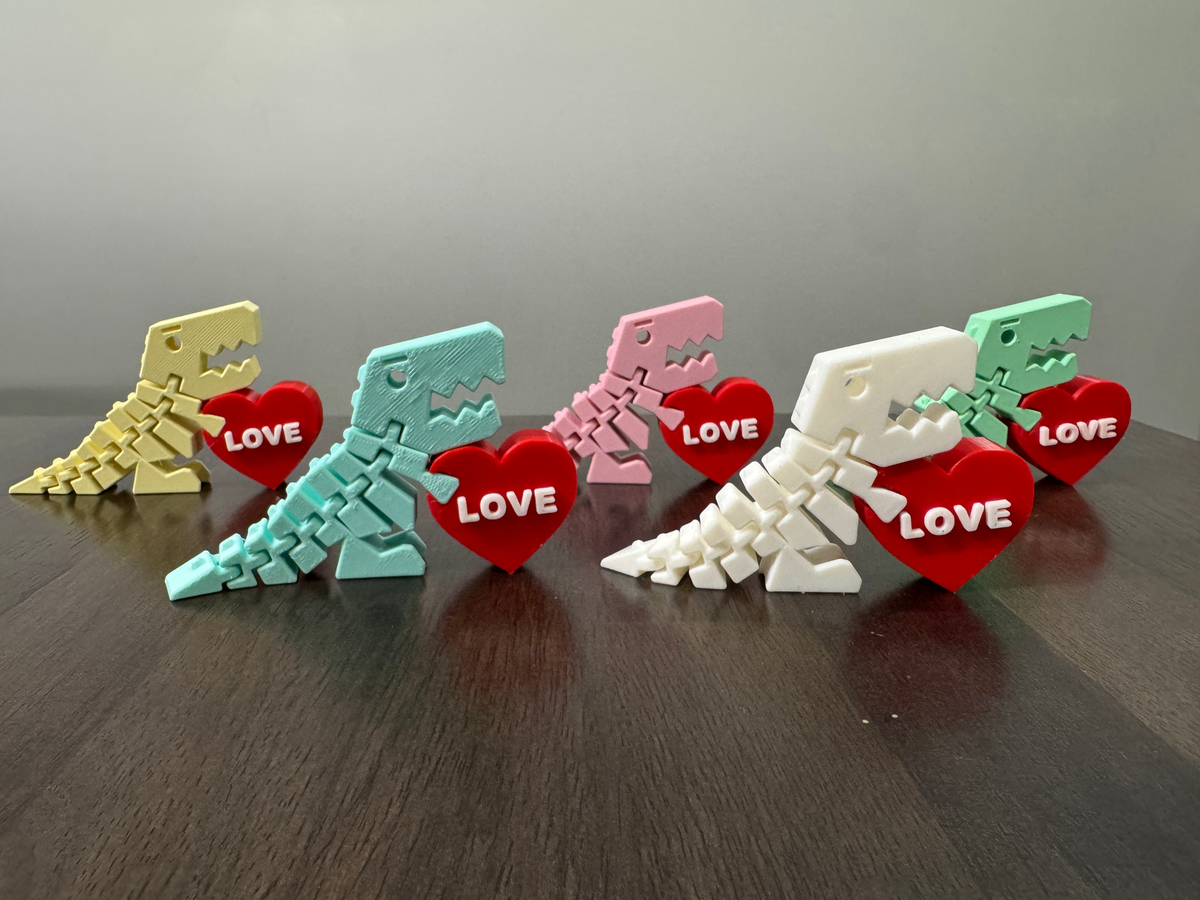 Flexi Dino Valentines — five articulated dinosaurs in yellow, mint, pink, white and green, each beside a red LOVE heart.