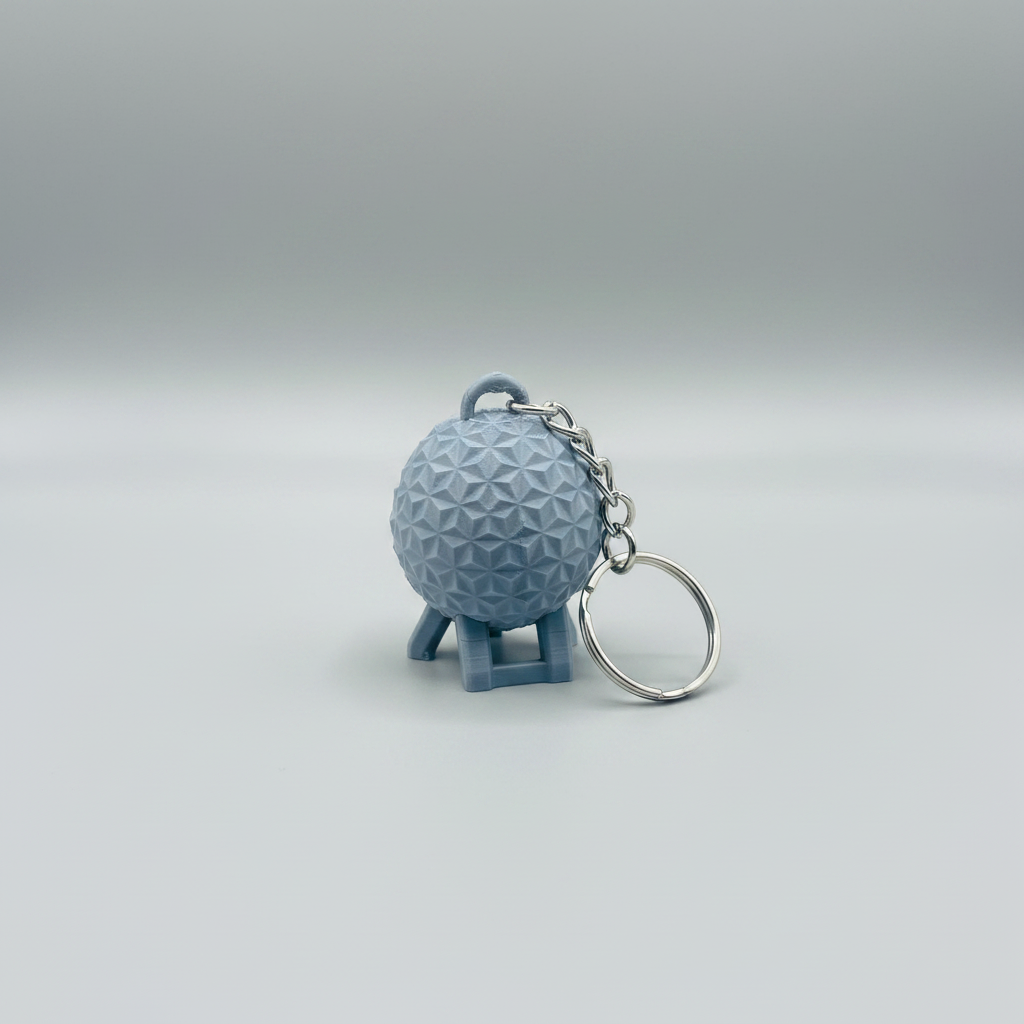 Geodesic Sphere Keychain — a small 3D-printed keychain shaped like a geodesic dome on a stand, attached to a silver metal chain and key ring, on a soft light-gray studio background.