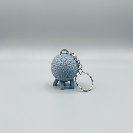 Geodesic Sphere Keychain — a small 3D-printed keychain shaped like a geodesic dome on a stand, attached to a silver metal chain and key ring, on a soft light-gray studio background.