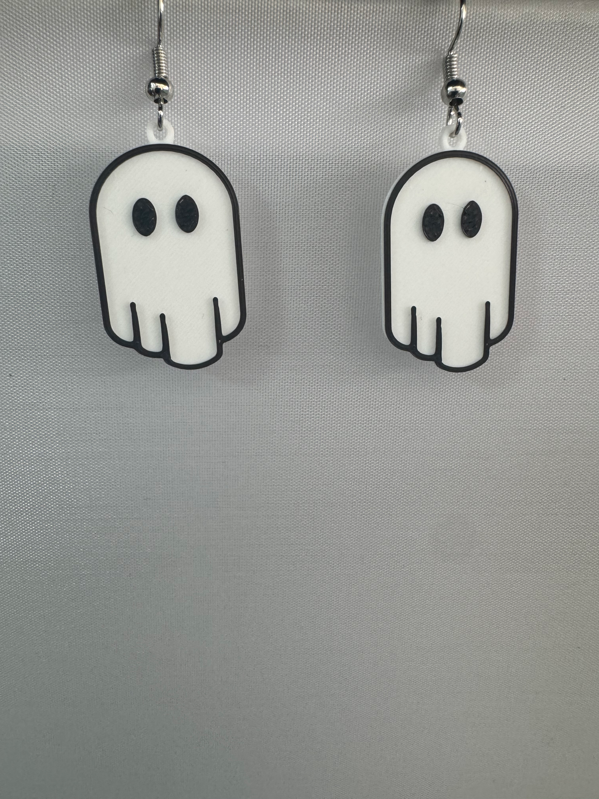 Ghost Earrings — a pair of white ghost-shaped earrings with black outlines and oval eyes, on silver hooks.