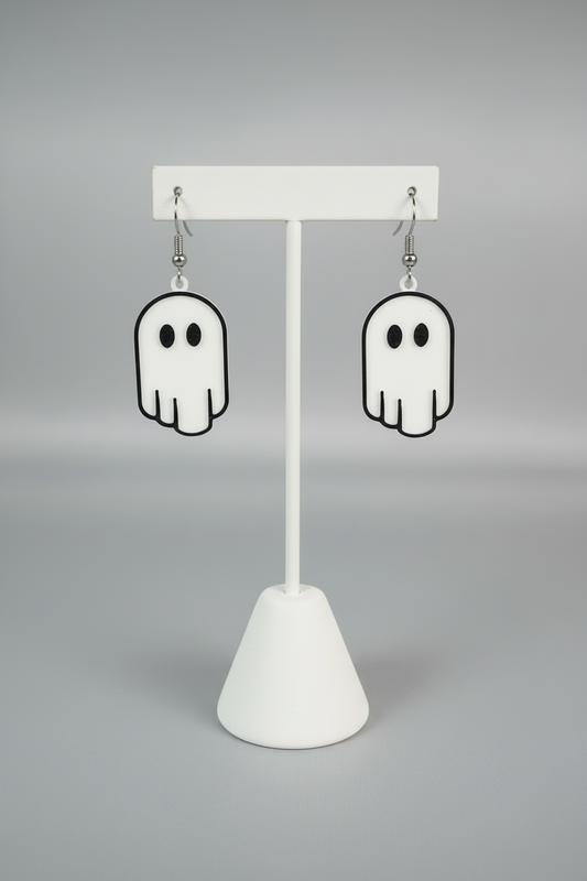 Ghost Earrings — a pair of white ghost-shaped dangle earrings with black outlines and silver hooks, on a soft light-gray studio background.