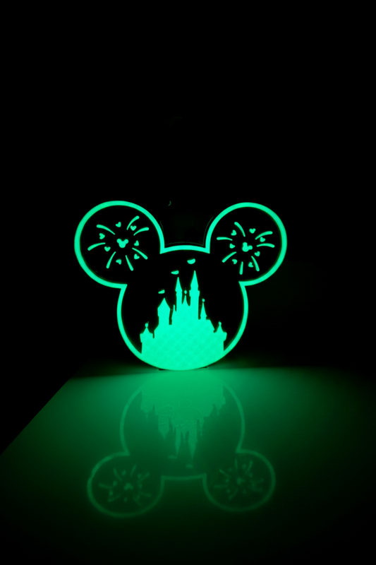 Glow-in-the-Dark Castle Soap Dispenser Holder — the same holder photographed with the lights off, its cut-out detailing glowing green.