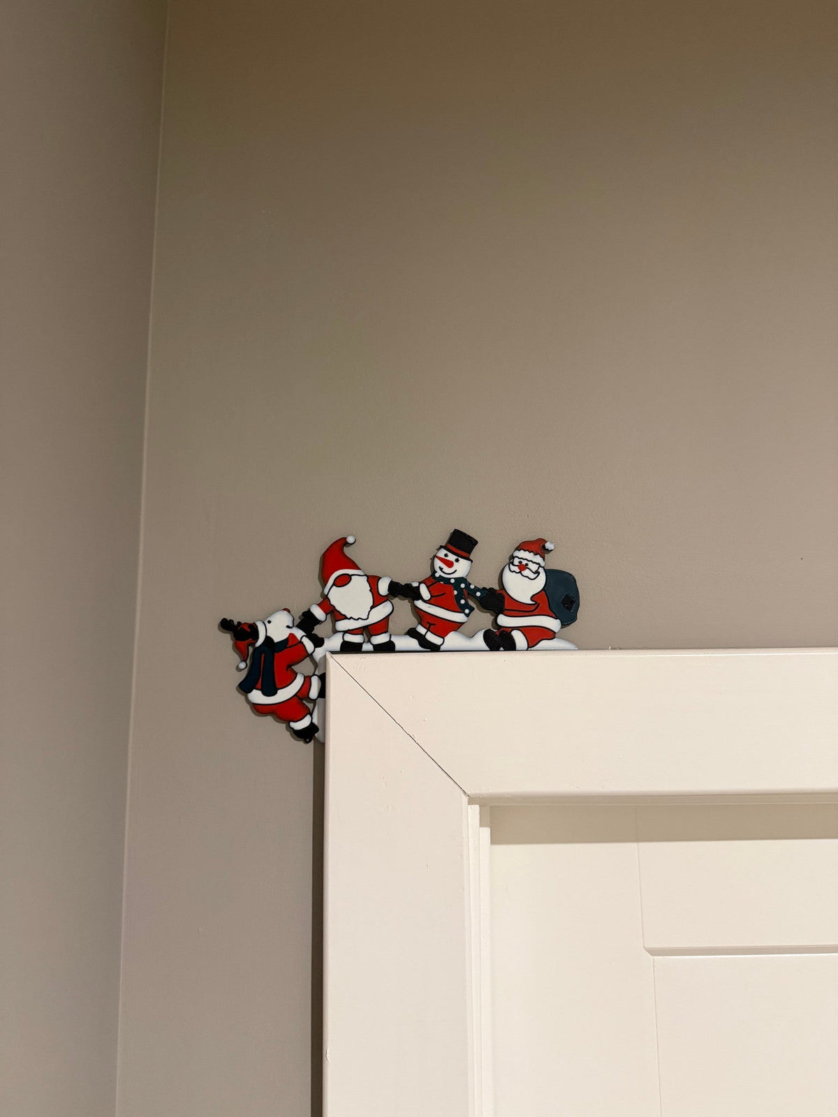 Mountain Climbing Crew Corner Door Topper — a row of small climbing figures in red and black perched along the top corner of a white door frame.