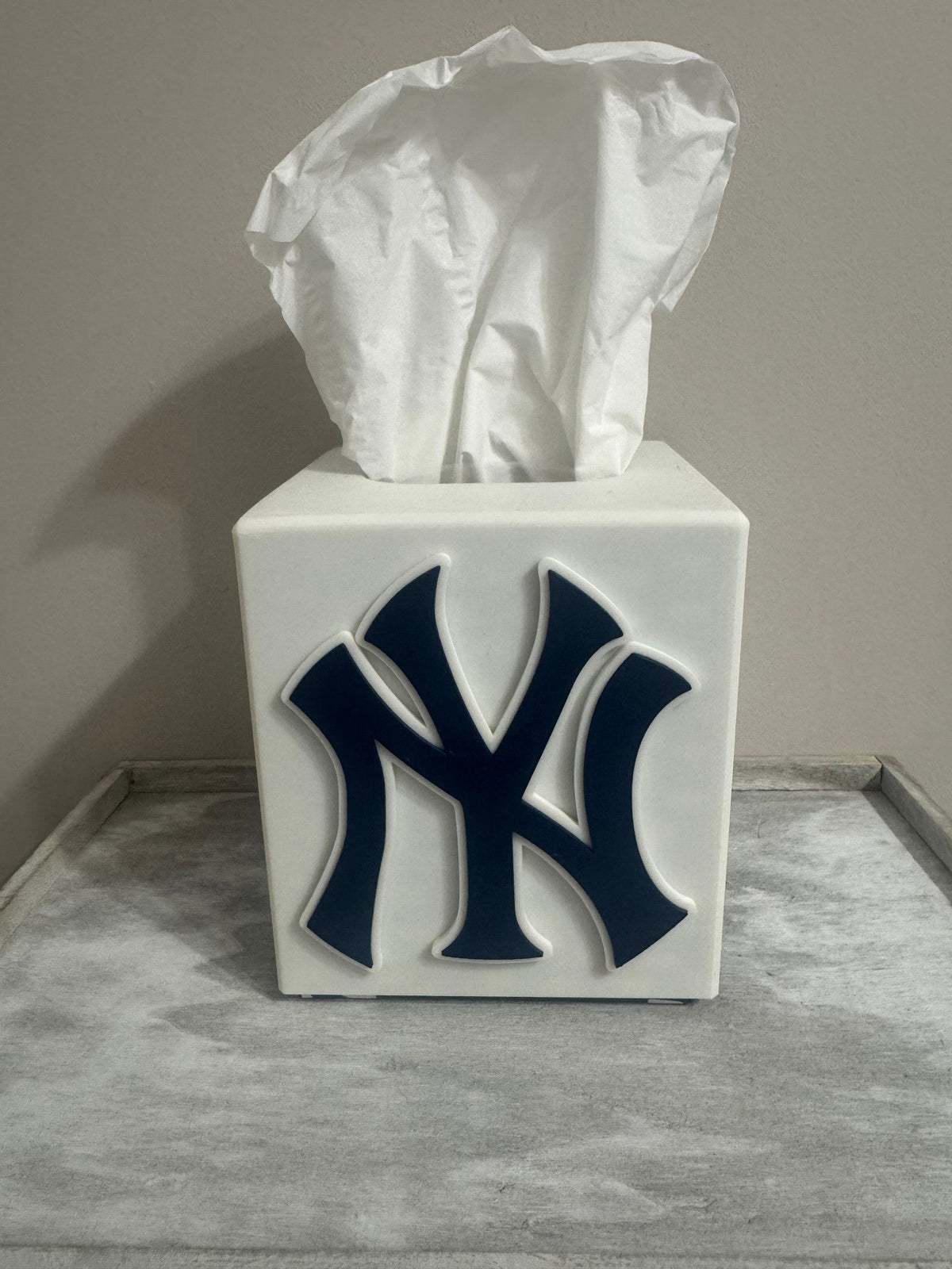 New York Tissue Box Cover — a white square tissue box cover with a navy blue raised monogram on the front, on a grey tray.