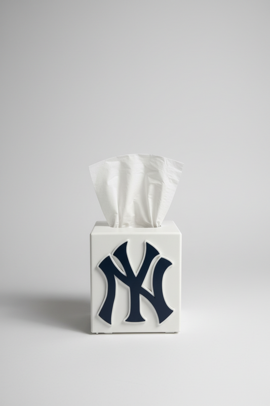 New York Tissue Box Cover — a white square tissue box cover with a raised navy monogram, tissue drawn through the top, on a soft light-gray studio background.