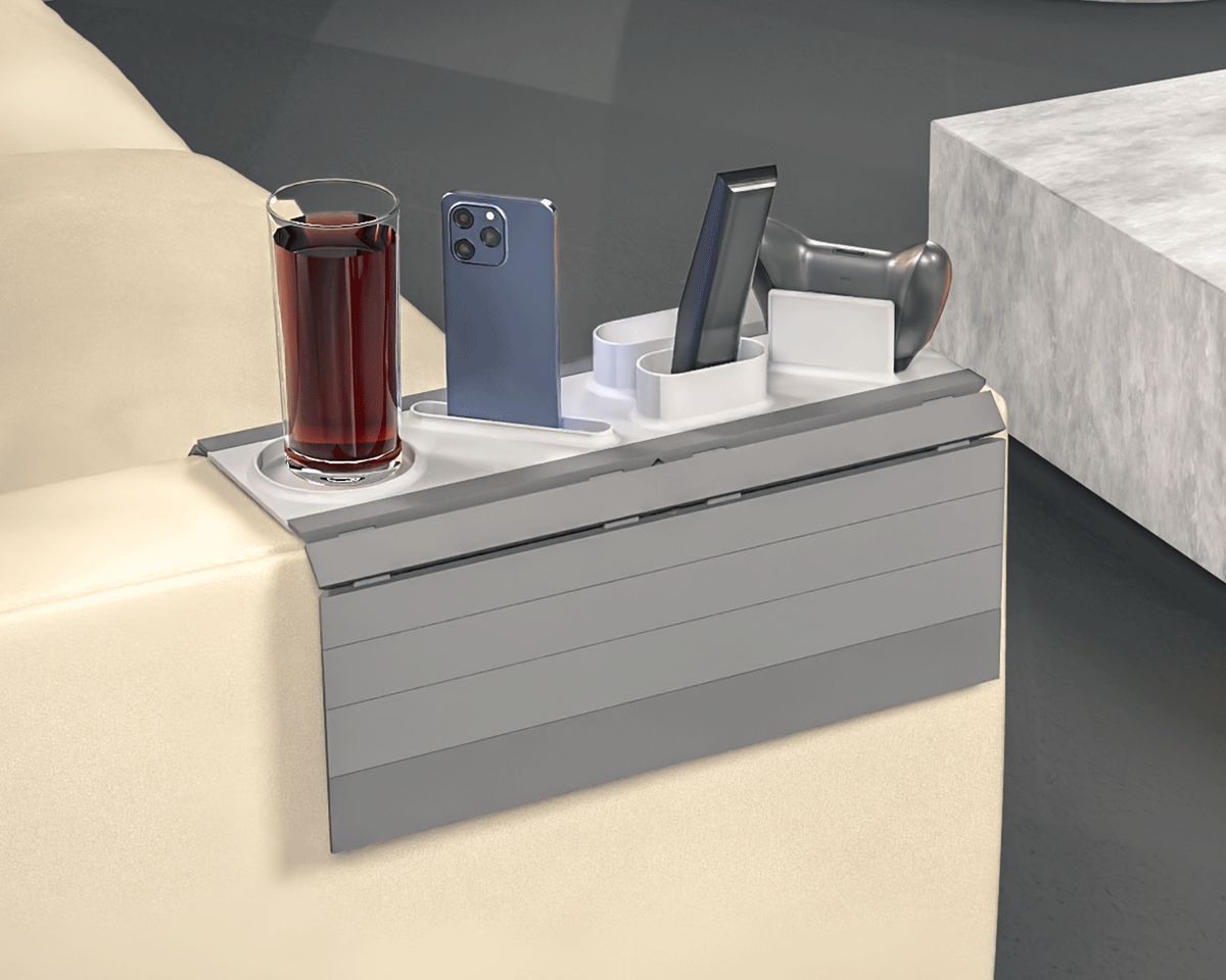 Player One Modular Sofa Side Table — the grey tray on a light sofa arm holding a drink, a phone, a remote and a controller stand.