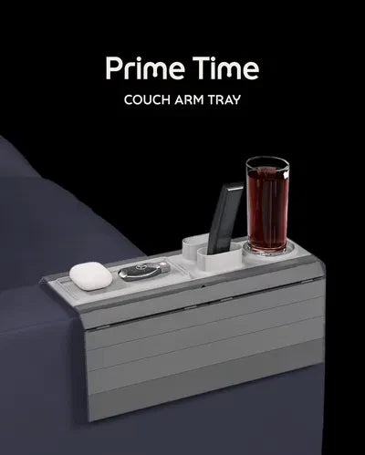 Prime Time Modular Sofa Side Table — a grey slatted couch arm tray with a cup holder, phone slot, remote slot and earbud tray, holding a drink and a phone.