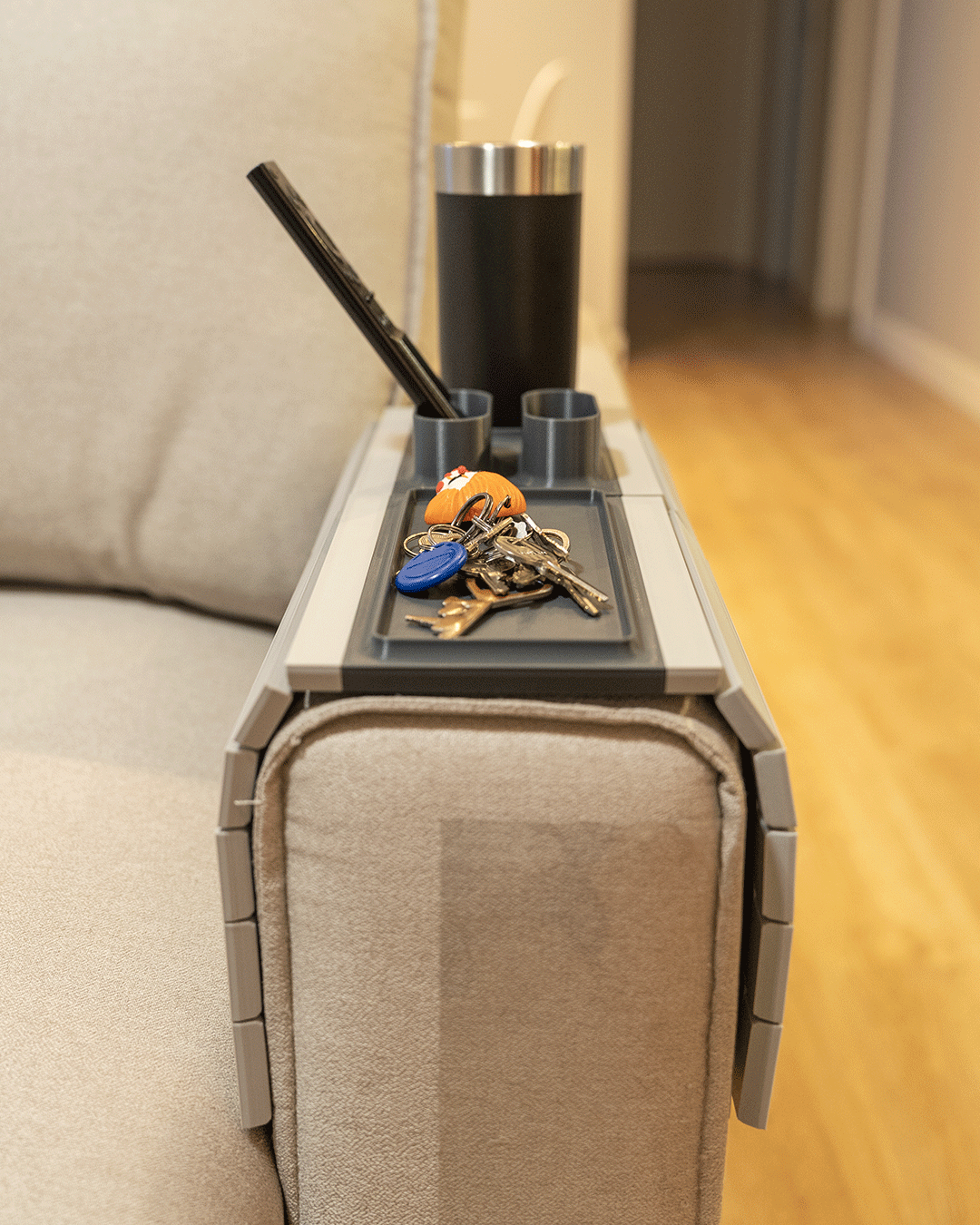 Prime Time Modular Sofa Side Table — the tray on a sofa arm holding a tumbler, a remote and a set of keys in the flat catch-all section.