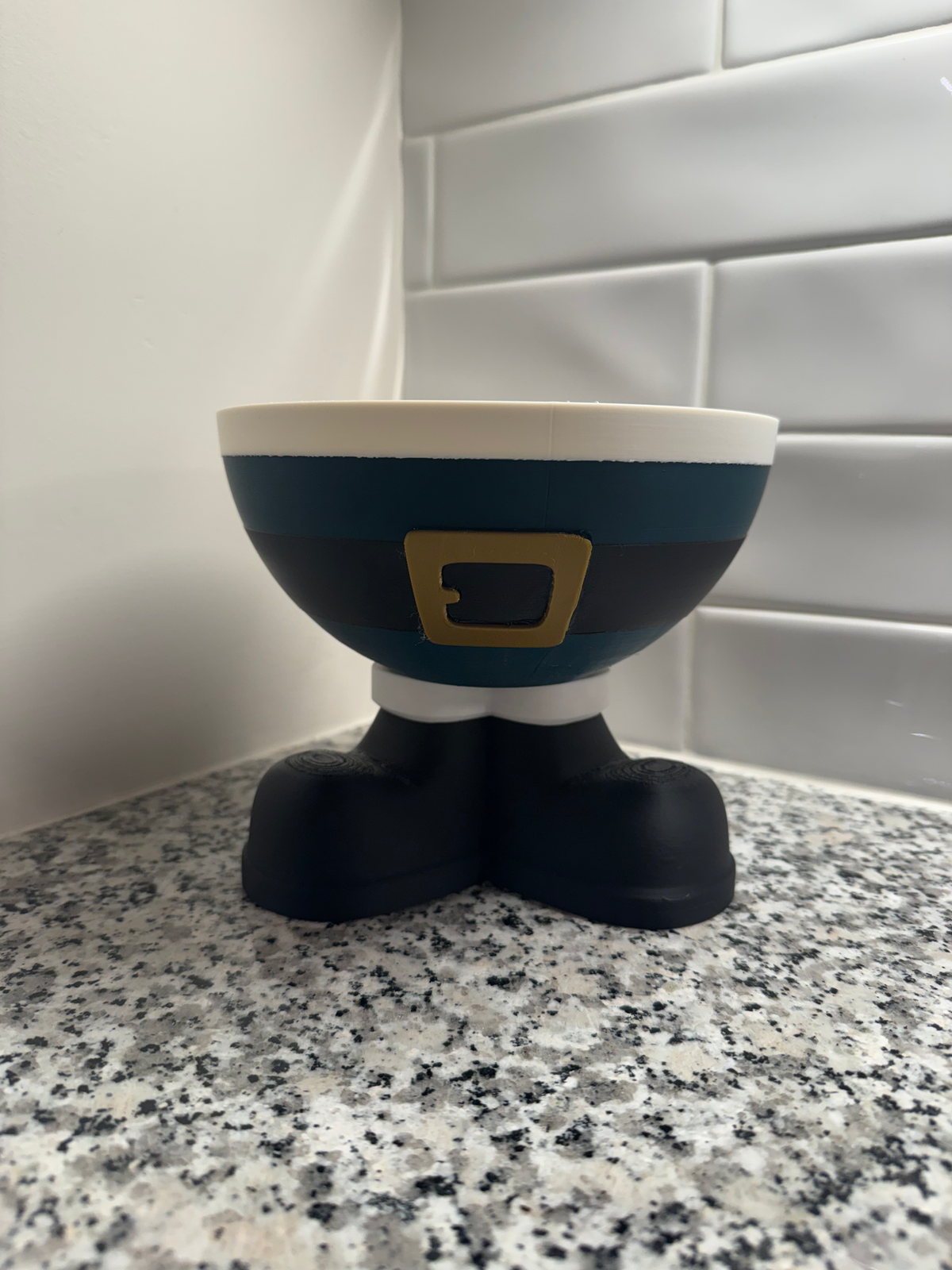 Santa Elf Trinket Bowl in green — a teal and cream bowl with a black belt and gold buckle on black boot feet.
