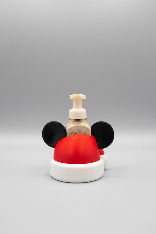 Santa Hat Mouse Soap Dispenser Holder — a beige pump bottle with a gold collar, shaped like a Santa hat with black mouse-ear details, on a soft light-gray studio background.