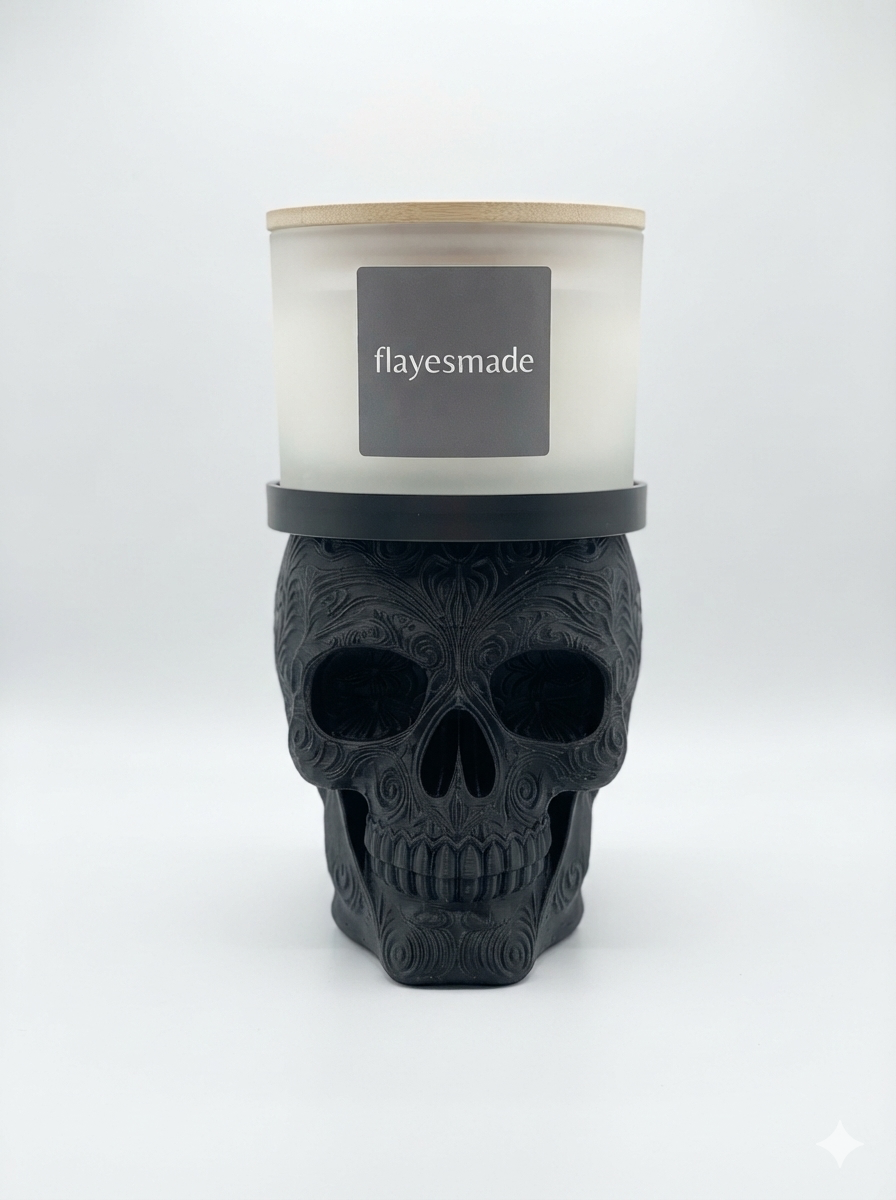 Sugar Skull Candle Holder — matte black skull with swirling filigree relief across the crown, brow, cheekbones and jaw, topped with a matching black collar ring holding a lidded frosted-white jar candle, on a soft light-gray studio background.