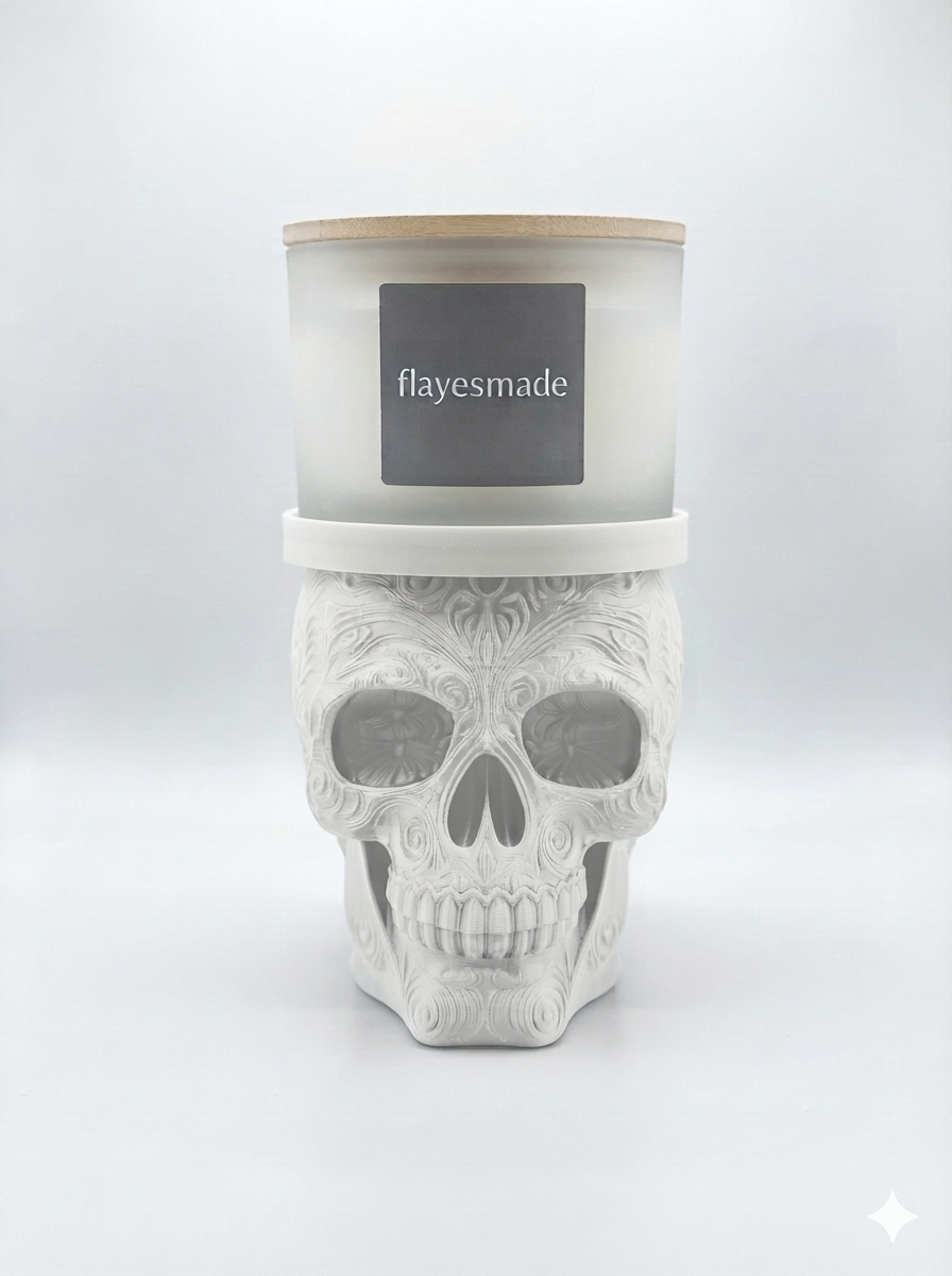 Sugar Skull Candle Holder — matte white skull with swirling filigree relief across the crown, brow, cheekbones and jaw, topped with a matching white collar ring holding a lidded frosted-white jar candle, on a soft light-gray studio background.