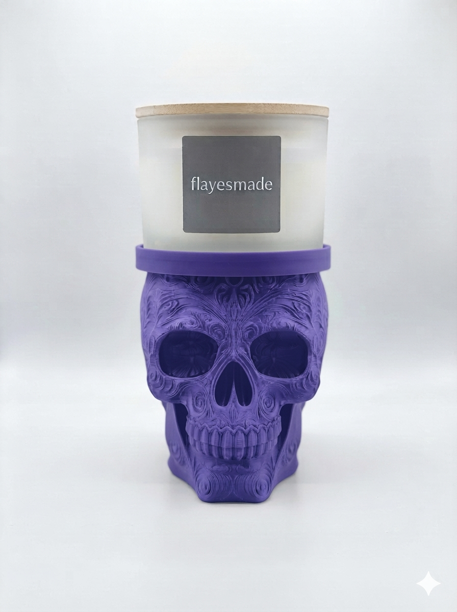 Sugar Skull Candle Holder — purple skull with swirling filigree relief across the crown, brow, cheekbones and jaw, topped with a matching purple collar ring holding a lidded frosted-white jar candle, on a soft light-gray studio background.