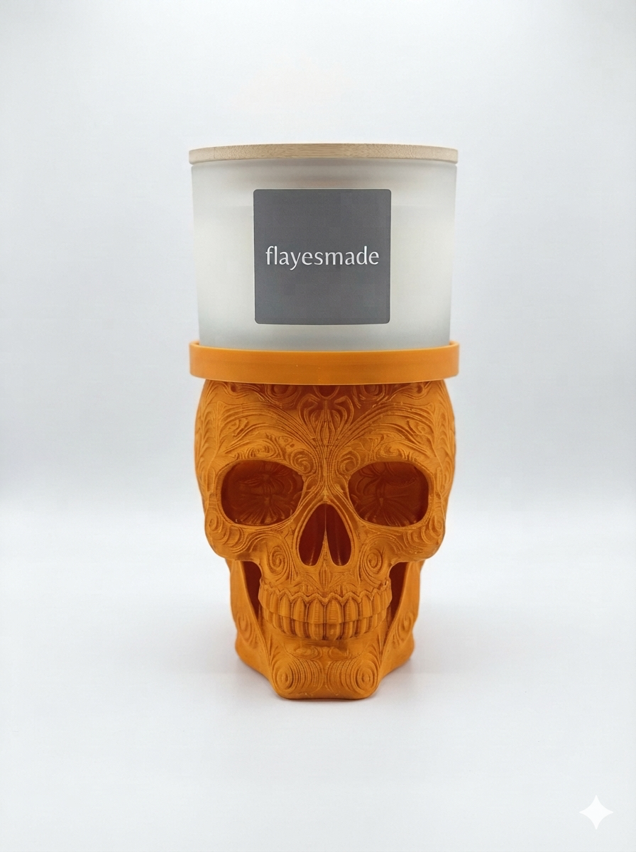 Sugar Skull Candle Holder — orange skull with swirling filigree relief across the crown, brow, cheekbones and jaw, topped with a matching orange collar ring holding a lidded frosted-white jar candle, on a soft light-gray studio background.