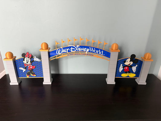 Theme Park Entrance Arch — a layered decorative archway with flagged towers and side panels, standing on a dark wood table.
